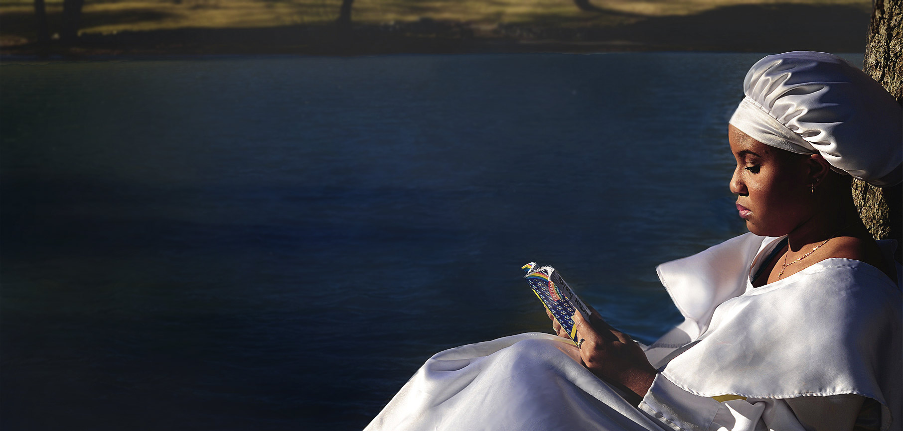 A sister in white sutana reading a Celestial Church hymnbook